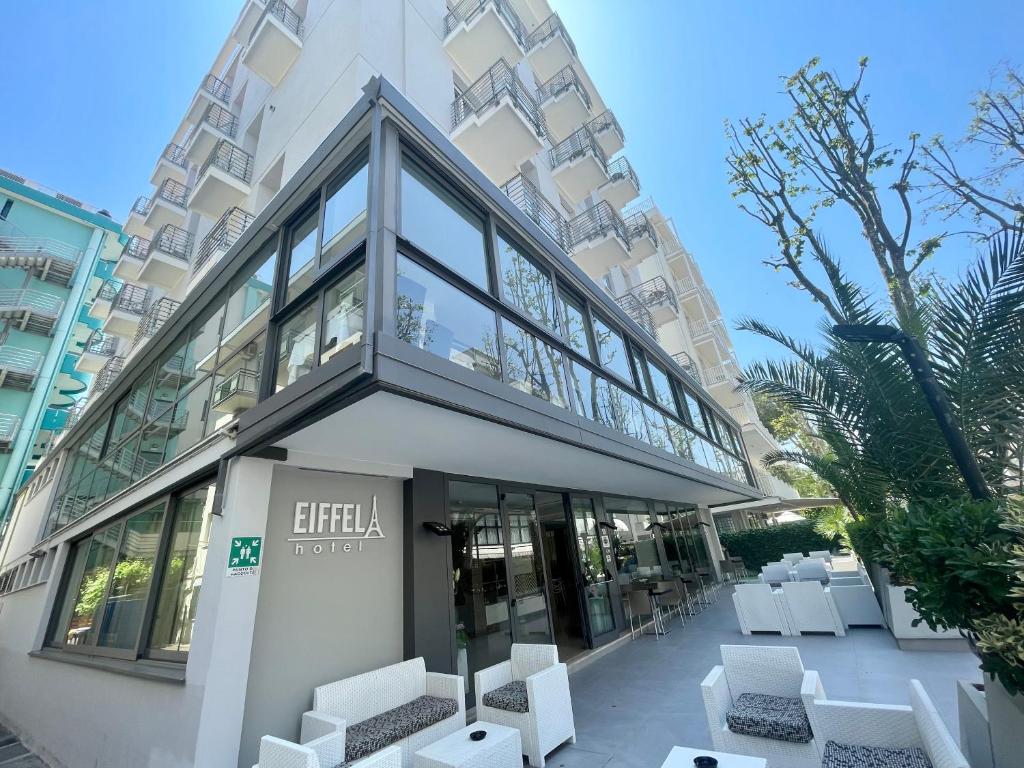 un edificio con sedie bianche di fronte a un edificio di Hotel Eiffel a Rimini