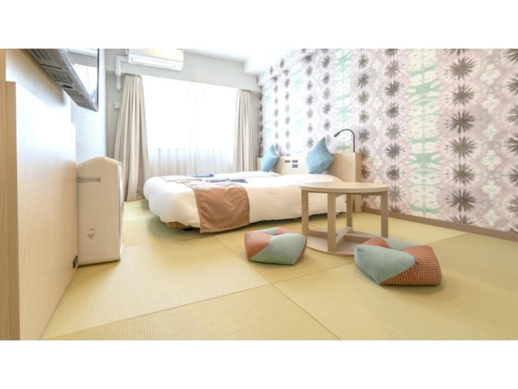 a bedroom with a bed and a table and chairs at La'gent Hotel Okinawa Chatan Hotel and Hostel - Vacation STAY 59141v in Fuenzan