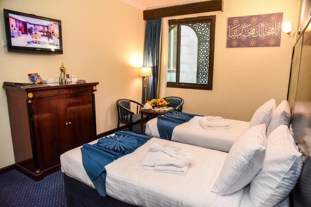 a hotel room with two beds and a television at Grand Plaza Al Madina in Al Madinah