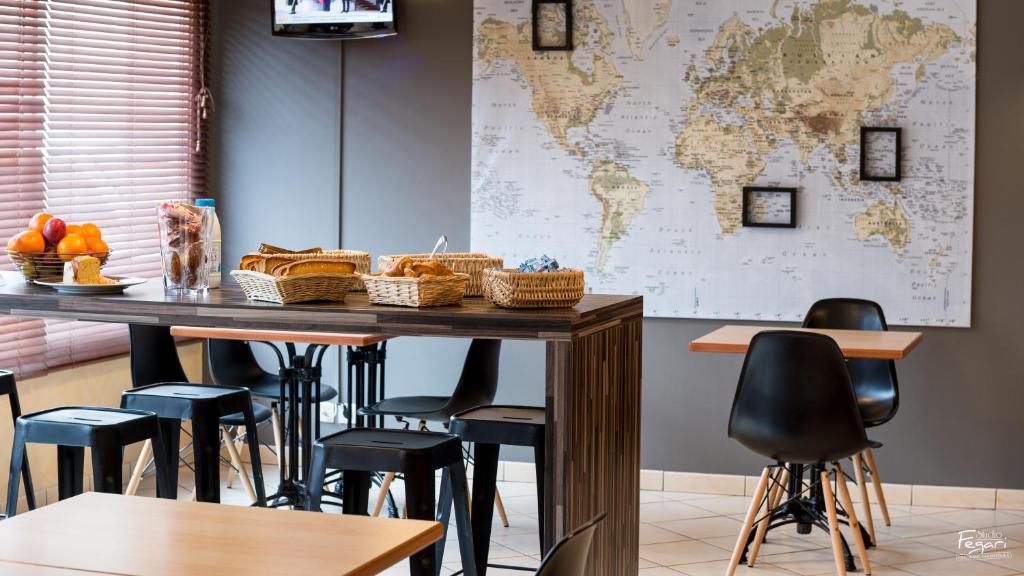 a table with chairs and a world map on the wall at Hotel First Rodez in Rodez