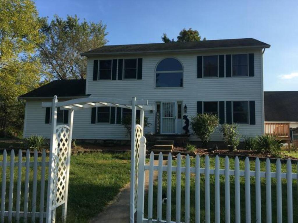 una cerca blanca frente a una casa blanca en Large Country Home en Bloomington