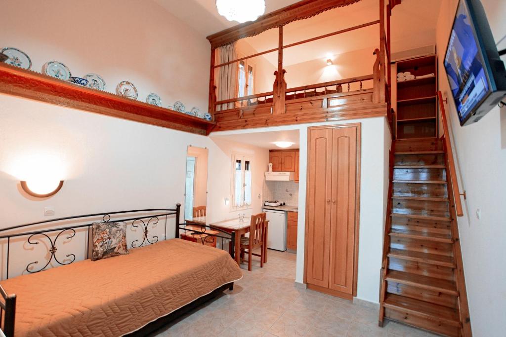 ein Schlafzimmer mit einem Bett und eine Treppe mit einem Fernseher in der Unterkunft Kostia Studios in Skyros