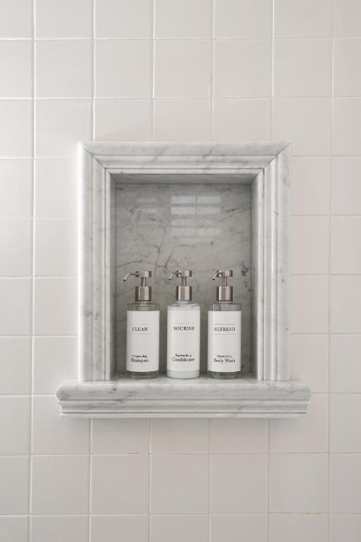 three bottles on a shelf in a bathroom at The Franciscan Hotel in Santa Barbara