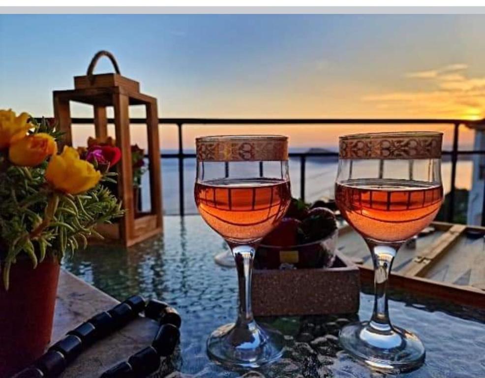 two wine glasses sitting on a table with the ocean in the background at Myrties House in Kalymnos