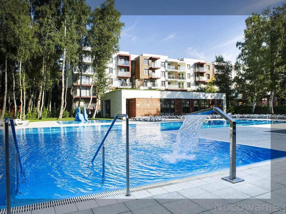 a swimming pool with a fountain in front of a building at Aparts Care Balic Polanki in Kołobrzeg