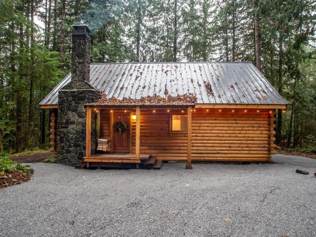 una cabaña en el bosque con techo de estaño en Creekside Cottage, en Glacier