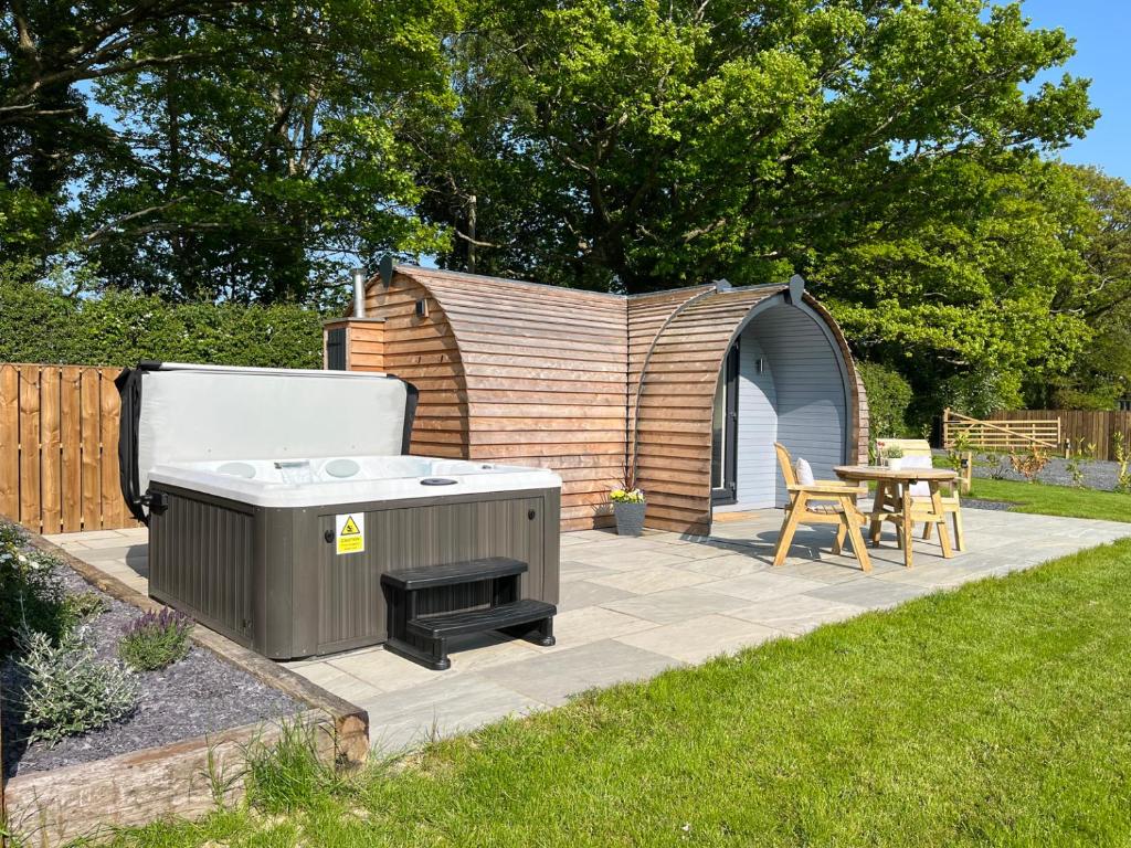 a backyard patio with a hot tub and a table at Yr Onnen in Ruthin