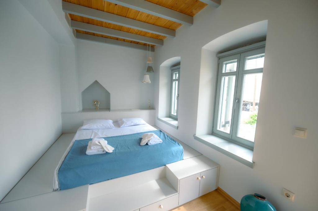 a bedroom with a bed with blue sheets and two windows at Villa Calliope in Kalymnos