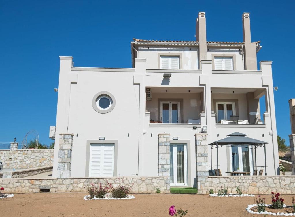 una casa blanca con un cielo azul en el fondo en Villa Amare, en Porto Heli