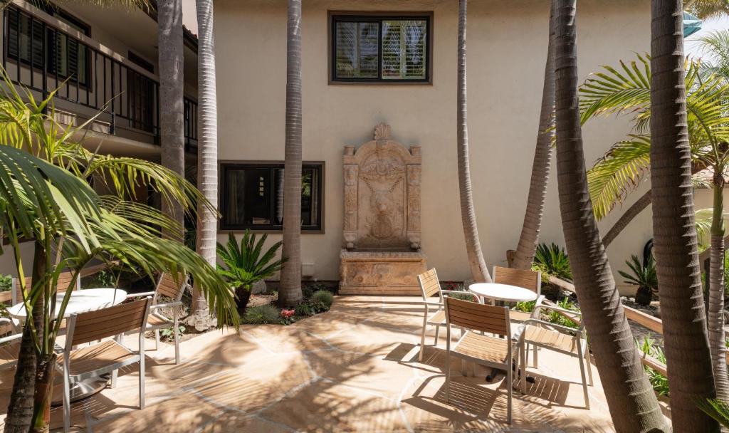a courtyard with palm trees and tables and chairs at The Franciscan Hotel in Santa Barbara