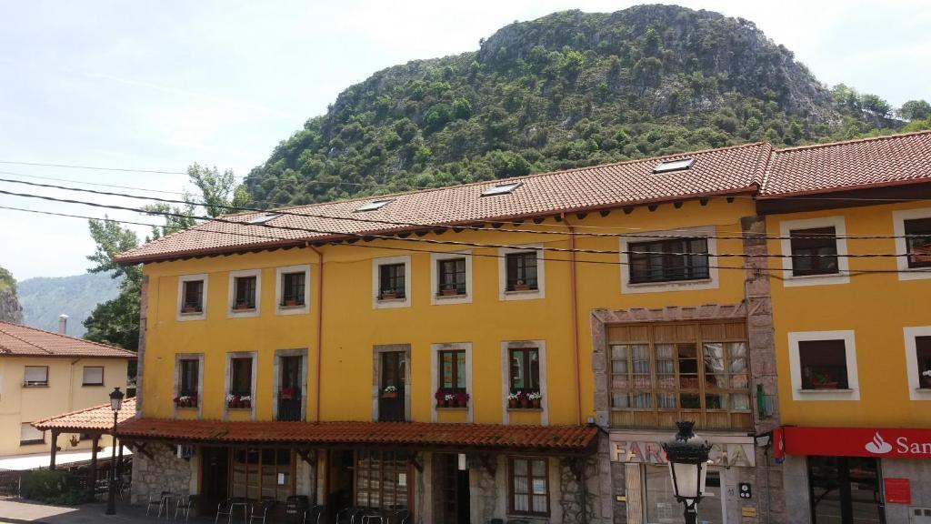 a yellow building with a mountain in the background at Hotel Rural Cabrales in Carreña de Cabrales 