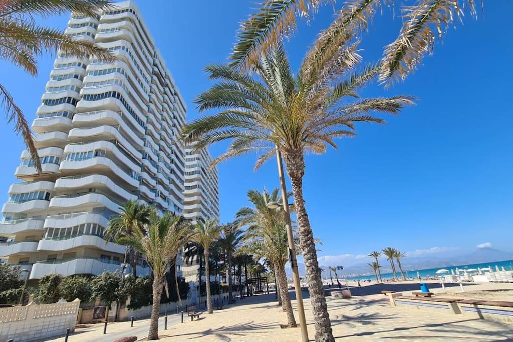 um hotel na praia com palmeiras e um edifício em Torres Blancas (Beach & Golf) em Alicante