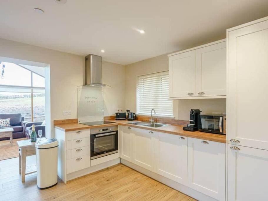a kitchen with white cabinets and a counter top at Tyr Ywen Cottage in Abergavenny