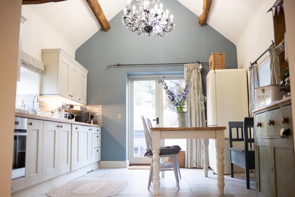 a kitchen with a table and a chandelier at The Forge - Beautiful Contemporary Barn - Hot Tub in Bridgnorth