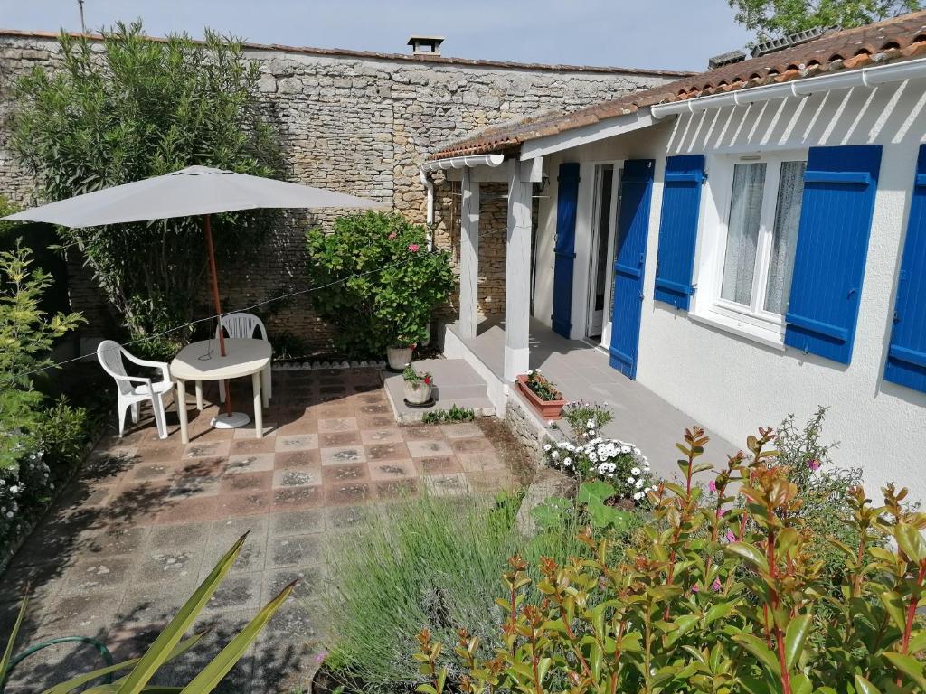 un patio avec un parasol, une table et des chaises dans l'établissement Jolie maison familiale oleronaise, à Saint-Georges-dʼOléron