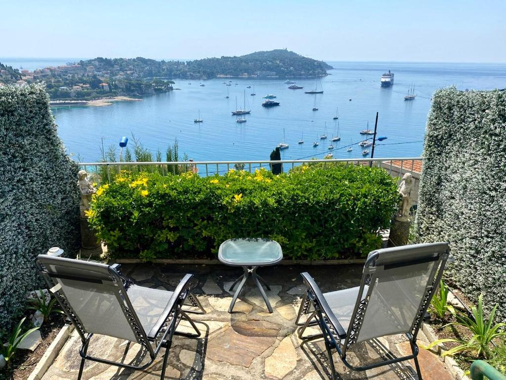 - deux chaises assises sur une terrasse donnant sur l'eau dans l'établissement Studio Bellevue, à Villefranche-sur-Mer