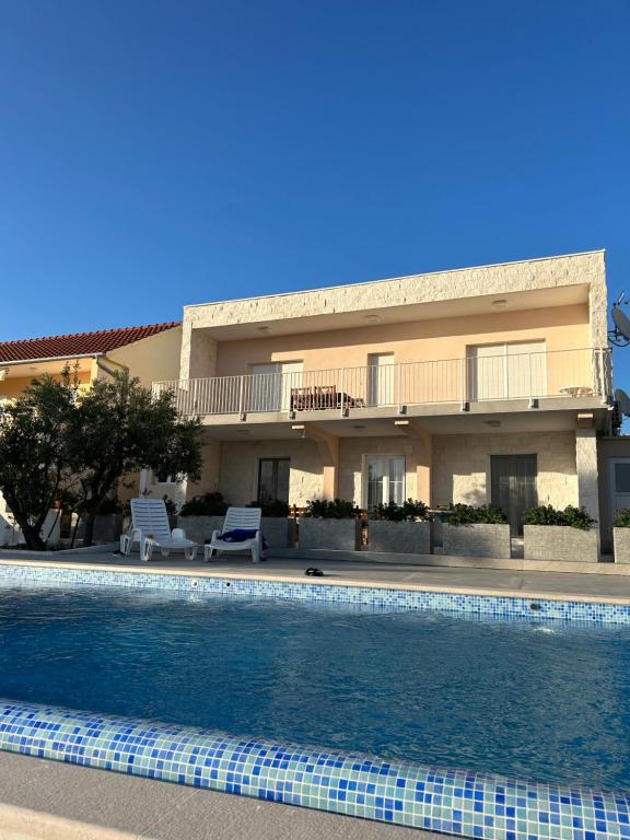 a hotel with a swimming pool in front of a building at Apartments Jurić in Brodarica