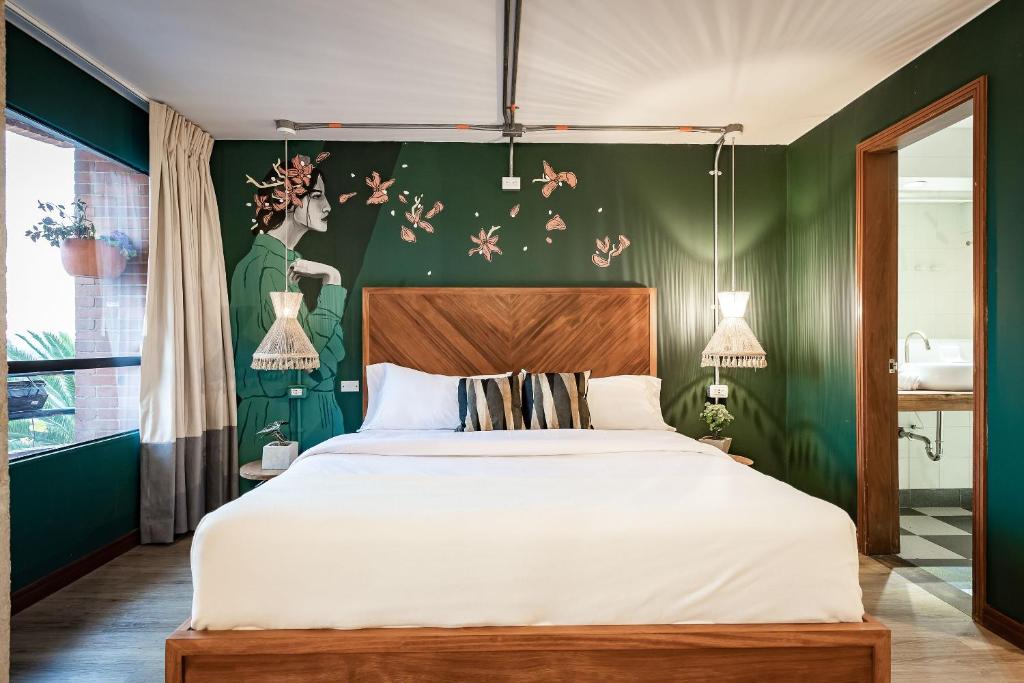 1 dormitorio con cama y pared verde en Selina Chapinero Bogota, en Bogotá