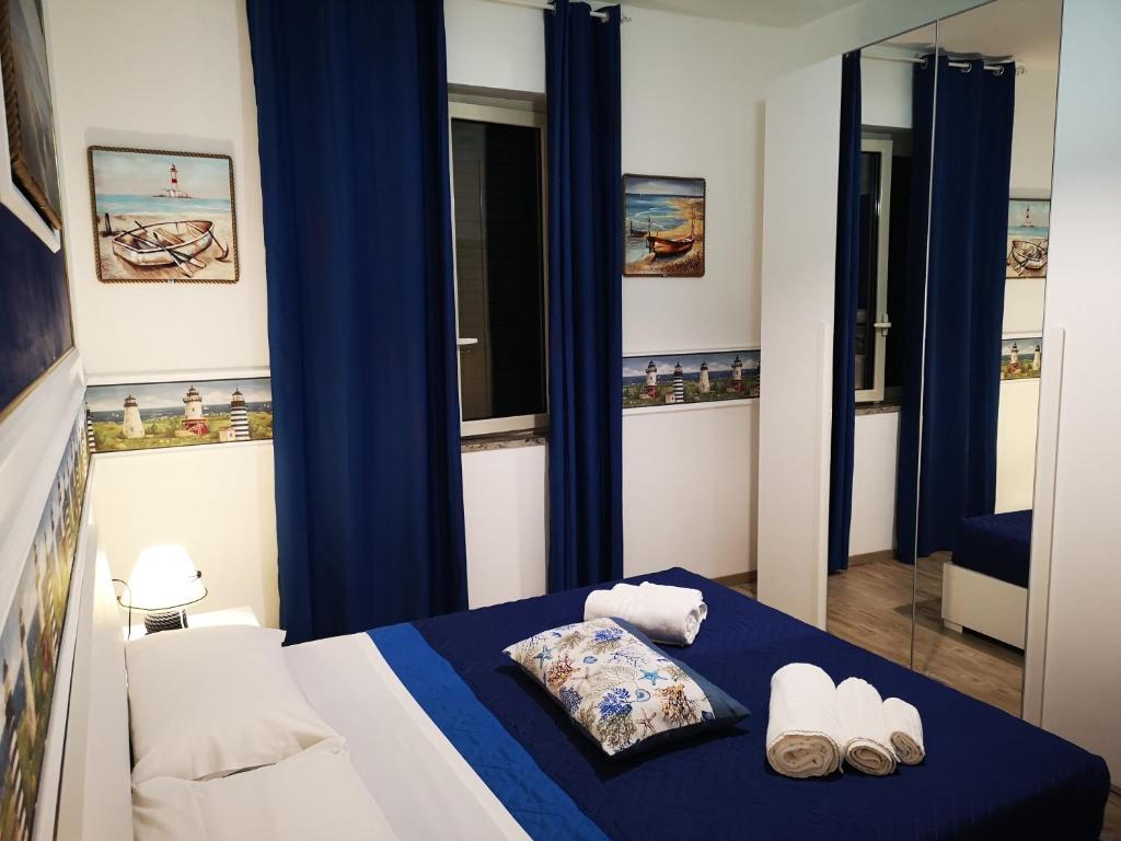 a bedroom with blue curtains and a bed with towels at La Casa di Alfonso in Marina di Camerota