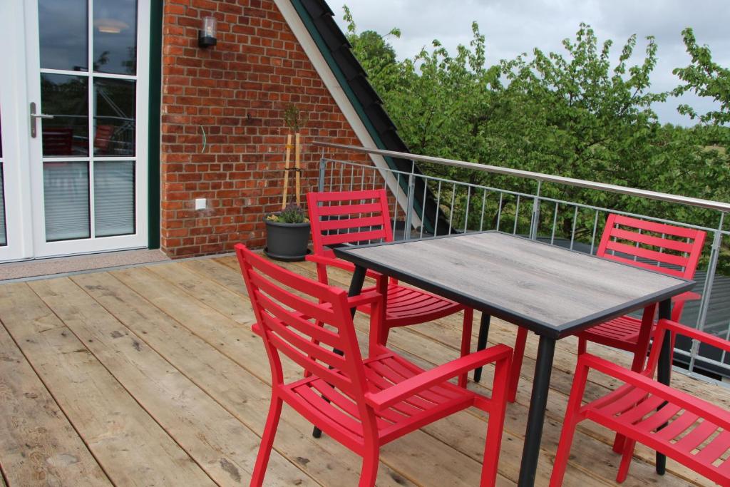 a table and four red chairs on a deck at Ferienwohnung Fritz in Jork