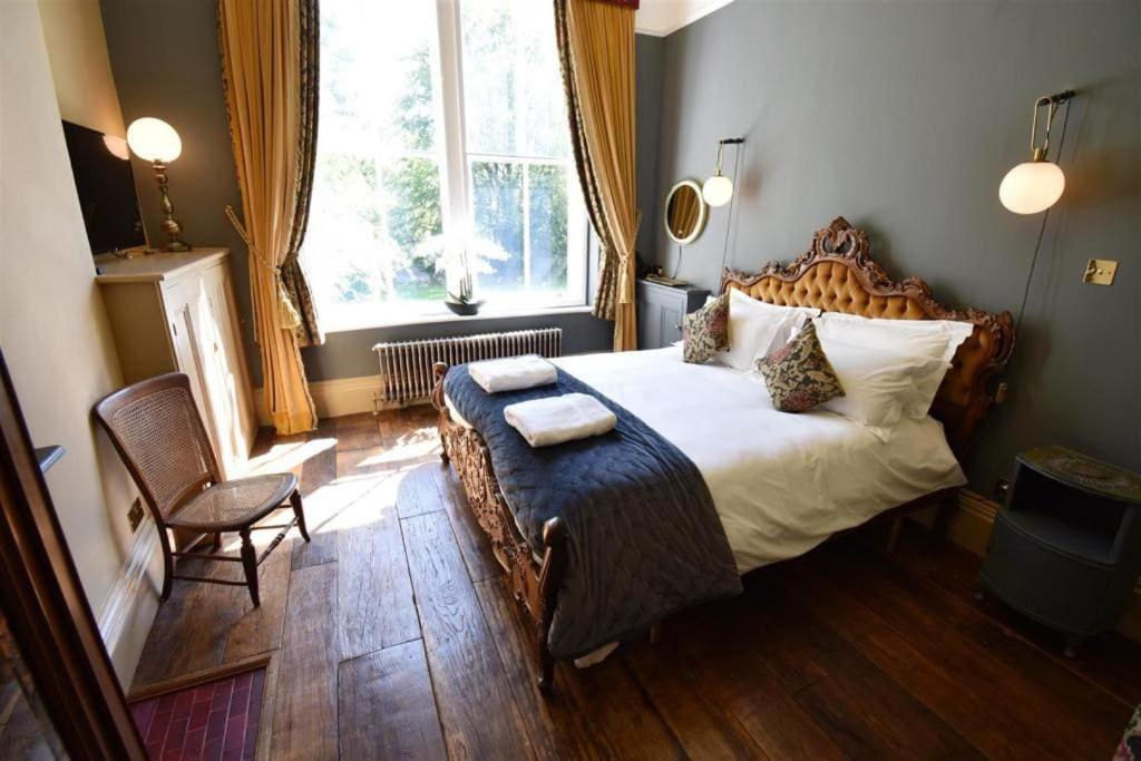 1 dormitorio con 1 cama, 1 silla y 1 ventana en The Huntress Suite en Buxton