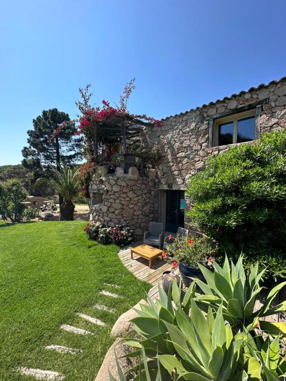 a stone house with a garden in front of it at Hôtel Ambassador Palombaggia in Porto-Vecchio