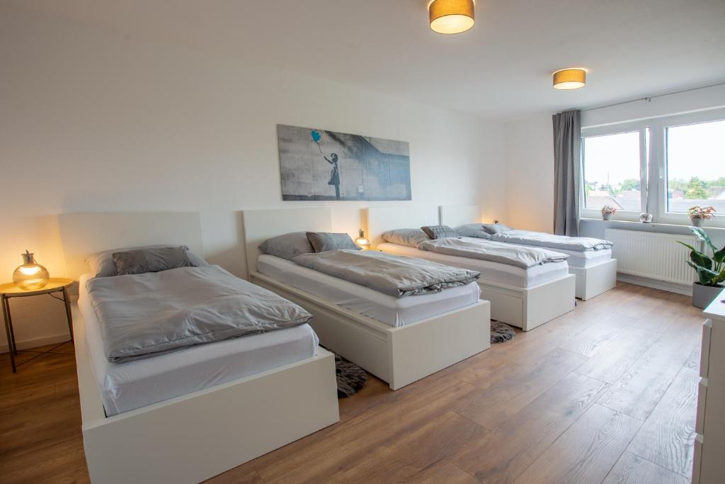 two beds in a room with wooden floors at City-House-Achern in Achern