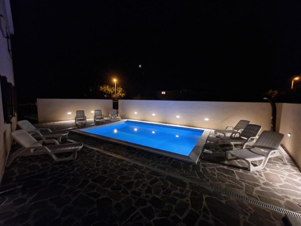 una piscina por la noche con sillas alrededor en The Setting Sun en Umag
