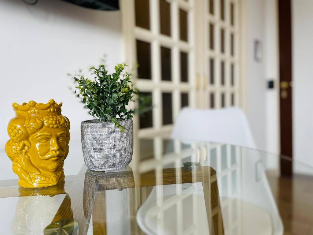 a glass table with a vase and a plant on it at Le Dimore del Corso in Catania