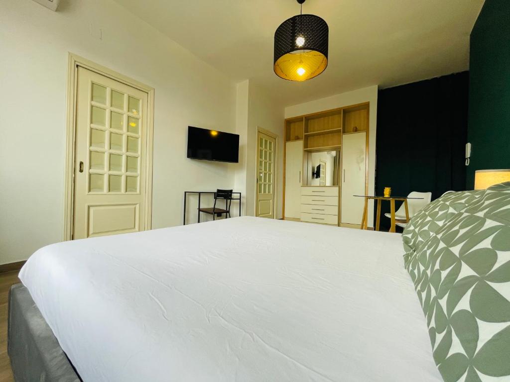 a bedroom with a large white bed and a tv at Le Dimore del Corso in Catania