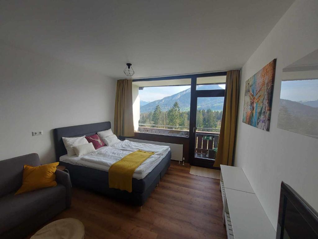 a bedroom with a bed and a couch and a large window at Ferienwohnung Panoramaglück in Bad Goisern