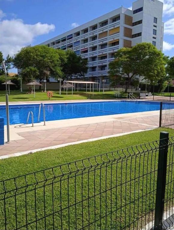 una valla frente a una piscina con un edificio en Estudio Taupe, en Matalascañas