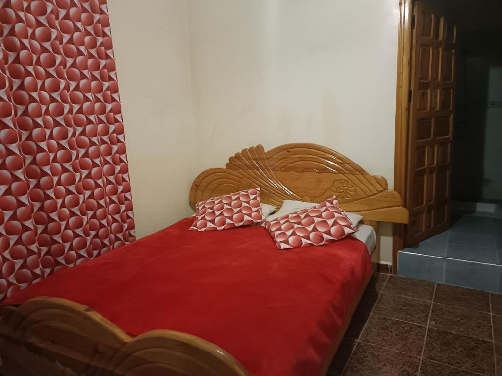 a bedroom with a red bed with two pillows on it at Dar badiawarda in Azilal