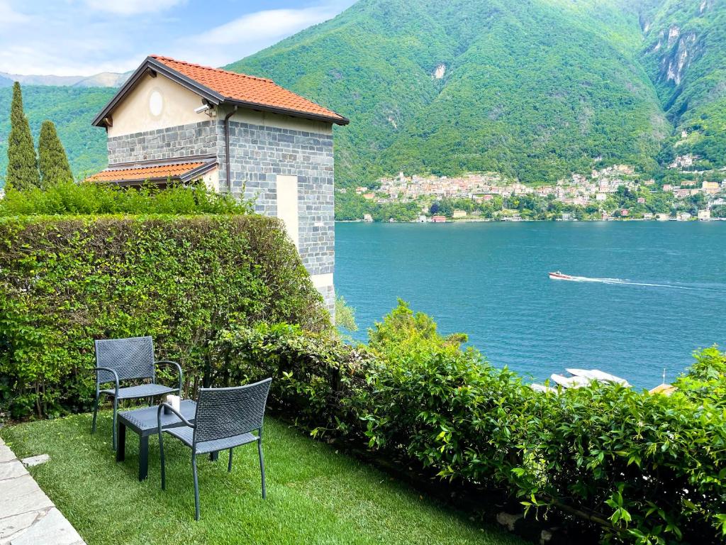 dos sillas sentadas en la hierba junto a un cuerpo de agua en Regina di Laglio - Free Parking, Garden, Lake View, en Laglio