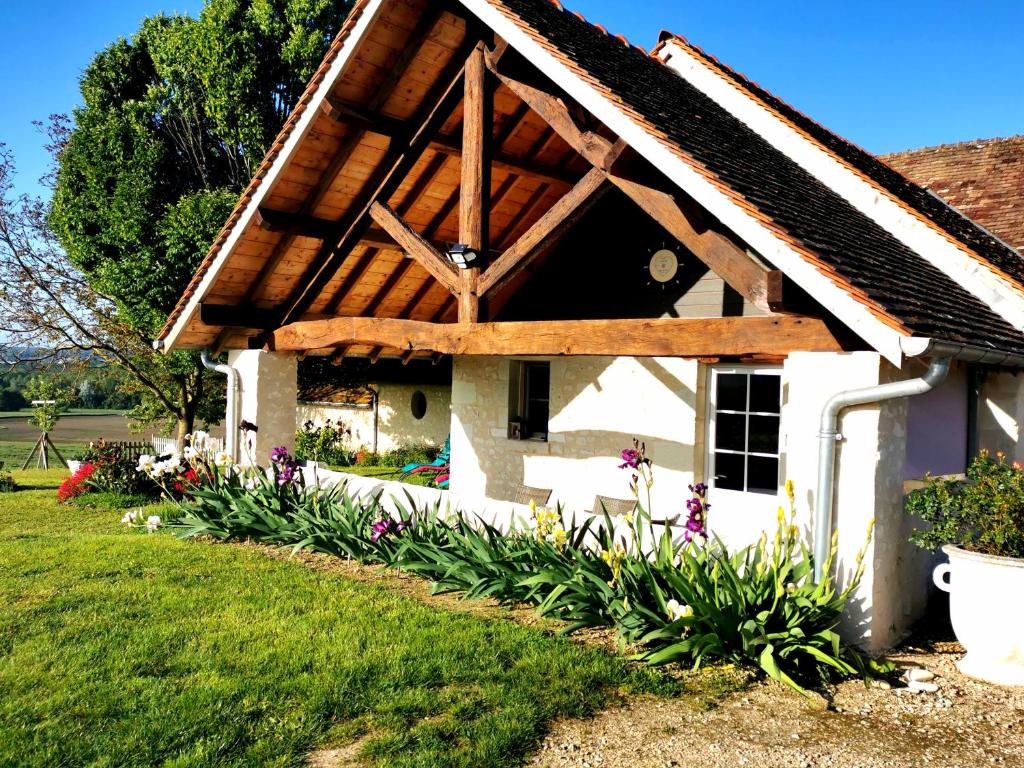 a cottage with a wooden roof and flowers at Gîte de charme dans un cadre calme et reposant in Châtellerault