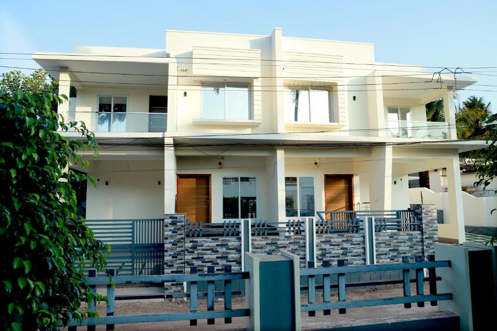 a white house with a blue fence in front of it at Clover Home in Thiruvalla