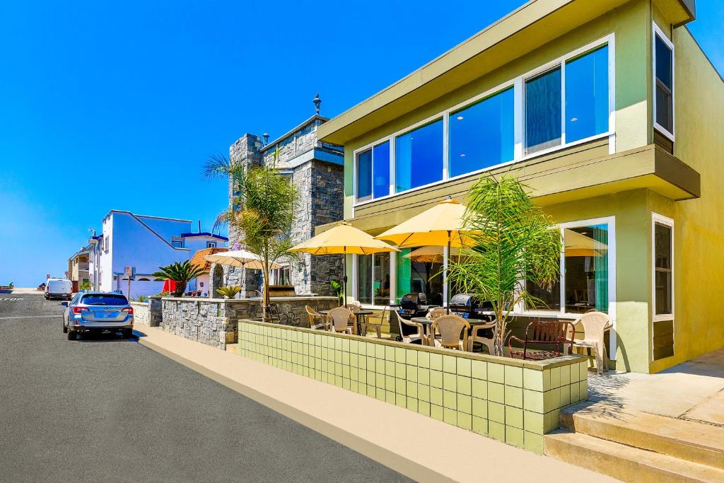 a building with a restaurant with chairs and umbrellas at Surf N Sand 1 & 2 in Newport Beach