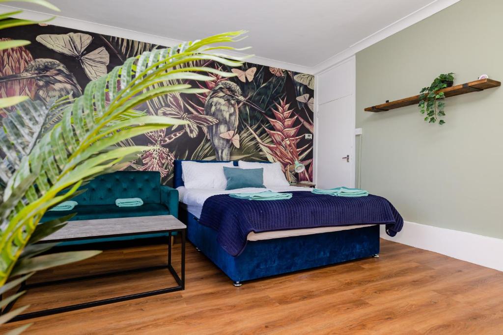- une chambre avec un lit bleu et une fresque murale dans l'établissement Super Central Location I Tropical Studio Apartment I Next to Brighton Beach and North Lanes, à Brighton et Hove