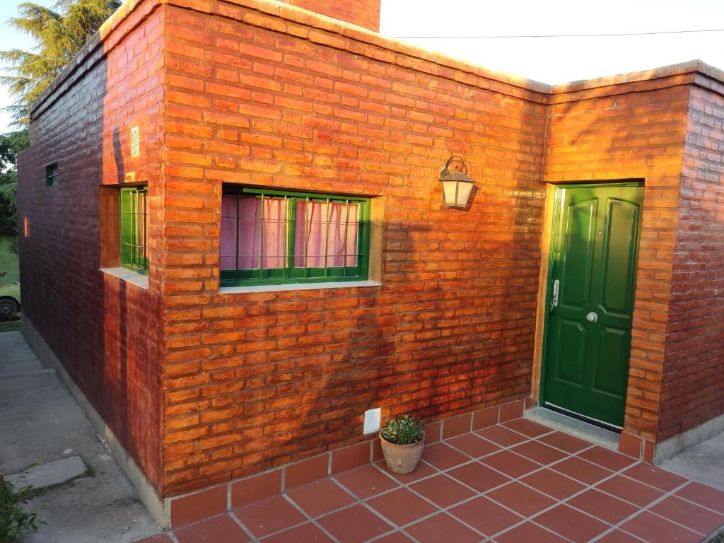 un edificio de ladrillo con 2 ventanas y una puerta verde en El Aromito en Alta Gracia