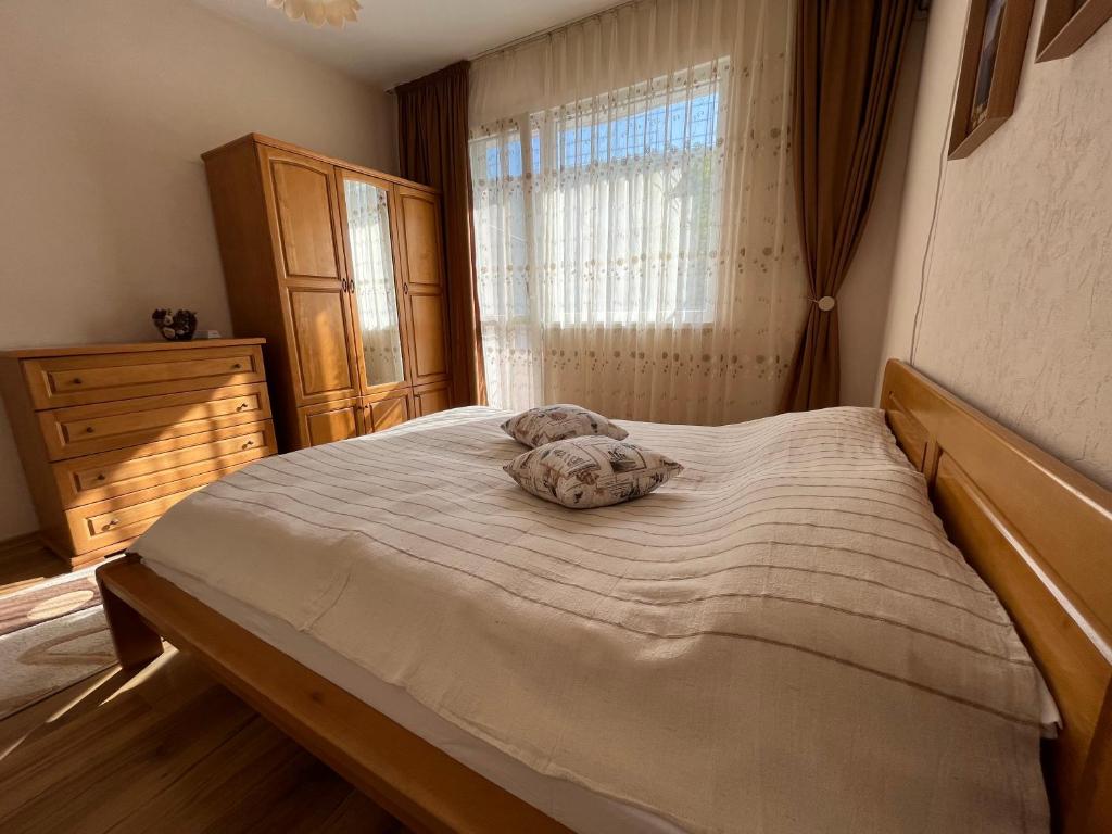 a bedroom with a large bed with a dresser and a window at Apartment Acacia in Varna City
