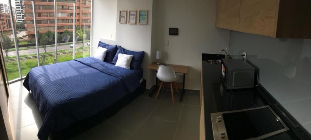 1 dormitorio con 1 cama azul y TV en Apto Luminoso y Acogedor Comodidad Garantizada, en Bogotá