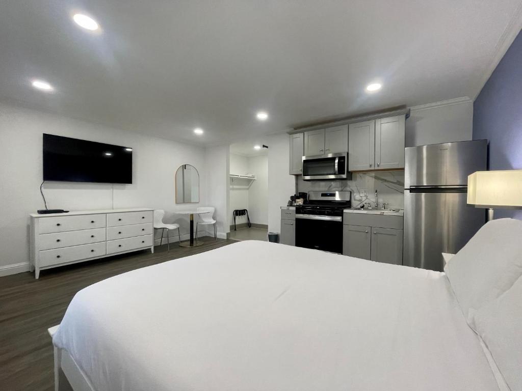 a large bedroom with a white bed and a kitchen at Budget Inn in Lompoc