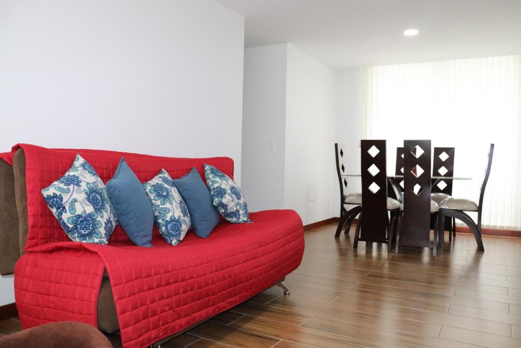 un sofá rojo con almohadas azules en la sala de estar. en Suite La Colina - Norte - Pasto en Pasto