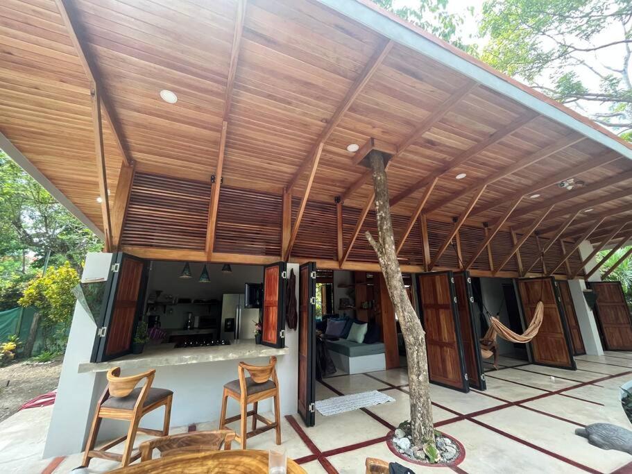 una casa con techo de madera y un árbol en el patio en Private NEW beach house with garden, en Cabuya