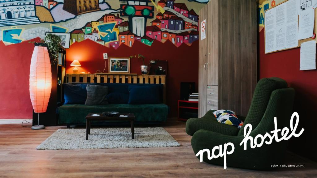 a living room with a green couch and a red wall at Nap Hostel Pécs in Pécs