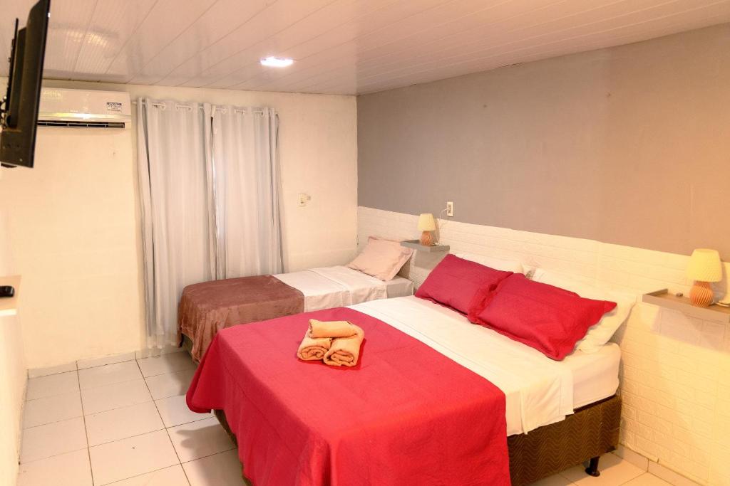 a bedroom with two beds and a red table at Noronha Economy Suítes - Hospedagem com melhor localização e custo benefício da ilha in Fernando de Noronha