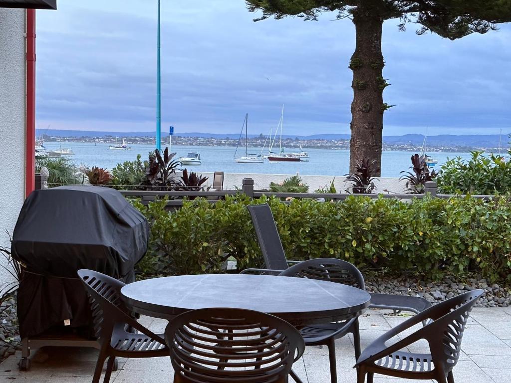 a table and chairs with a view of the water at The Bay The Beach The Mount The Best in Mount Maunganui