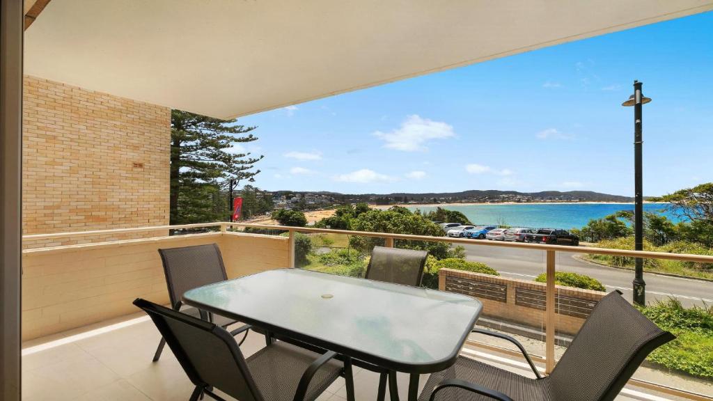 Una mesa y sillas en un balcón con vista al mar. en Roweshaven Amazing Views, Close To Beach Accom Holidays, en Terrigal