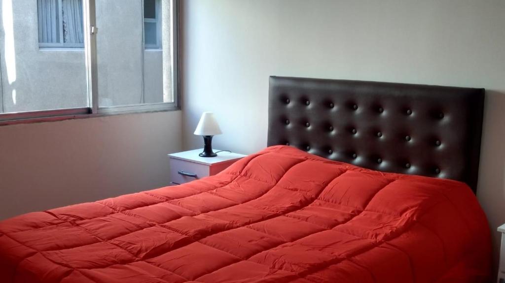 1 cama con edredón rojo en un dormitorio en DEPARTAMENTOS MENDOZA PEATONAL 2 en Mendoza