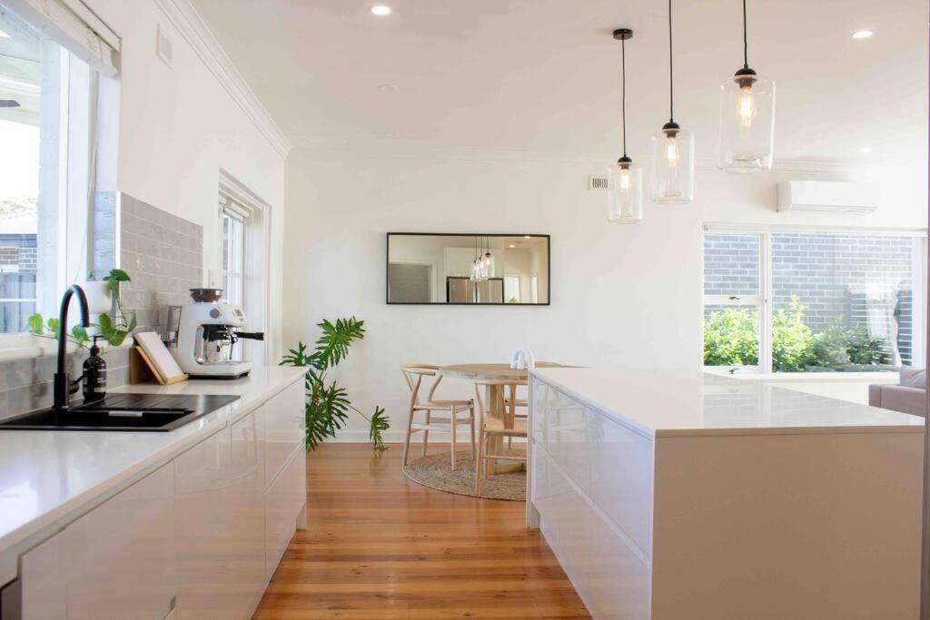 a white kitchen with a counter and a table at The Beech House-Hill views, peaceful location, 2BR in Tanunda